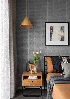 a bed room with a neatly made bed next to a lamp and pictures on the wall