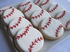 decorated cookies in the shape of baseballs on a plate with white icing and red piping