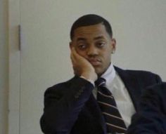 a man wearing a suit and tie sitting in front of a mirror