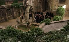 a group of people standing in front of an old building with ivy growing on it