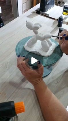 a woman is working on a sculpture with her hands and paintbrushes in front of her