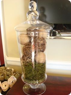 a glass jar filled with balls of yarn and moss