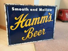 a blue sign that says hamm's beer on the floor next to a red suitcase