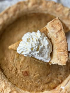 a piece of pie with whipped cream on top is being held up by a fork