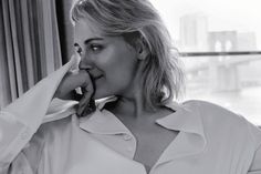 a black and white photo of a woman talking on a cell phone in front of a window