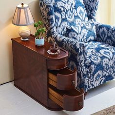 a blue and white patterned chair next to a table with a lamp on top of it