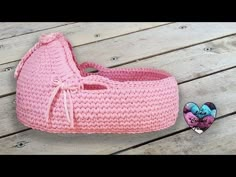 a pink crocheted basket sitting on top of a wooden table next to a small stuffed animal