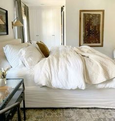 a bed with white sheets and pillows in a room