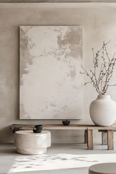 a large white vase sitting on top of a wooden table next to a wall mounted painting