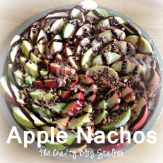 apple nachos with chocolate topping in a glass bowl on top of a wooden table