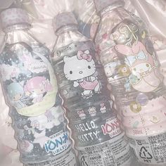 three hello kitty water bottles sitting on top of a plastic bag