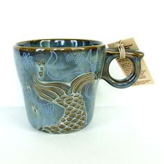 a coffee cup with a fish design on the side and a tag attached to it