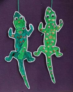 two paper cut out lizards hanging from strings