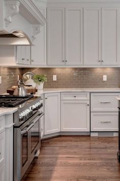 a kitchen with white cabinets and wood floors