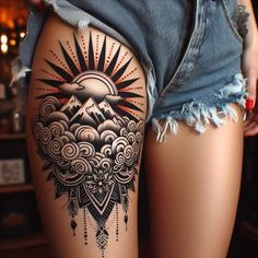 a woman's thigh with an artistic tattoo design on her leg and the sun in the sky