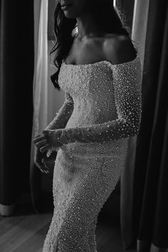 a woman in a white dress is standing near a window and posing for the camera