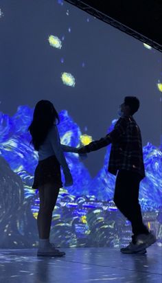 a man and woman standing in front of a large screen with blue lights on it