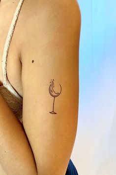 a woman's arm with a tattoo on it and a wine glass in the middle