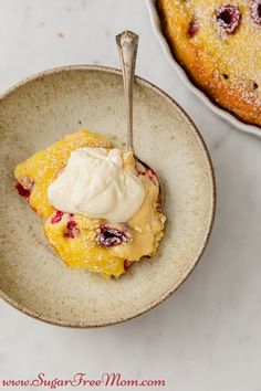 a bowl filled with fruit and cream next to a plate full of cake on a table