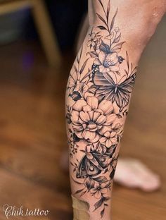 a close up of a person's leg with flowers and butterflies on the legs