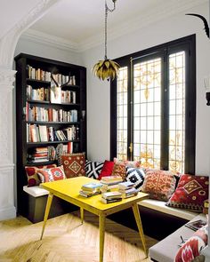 a living room filled with lots of furniture and bookshelves next to a window