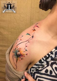 a woman with a tattoo on her chest is looking down at her stomach and has flowers growing out of it