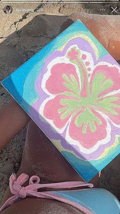 a painted box sitting on top of someone's feet in the sand at the beach