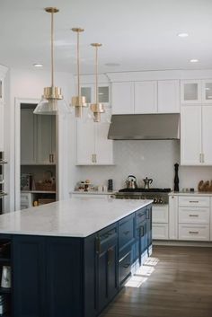 a kitchen with white cabinets and blue island