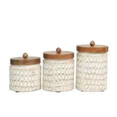 three white ceramic canisters with wooden lids