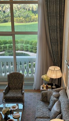 a living room filled with furniture and a large window overlooking a lush green park behind it