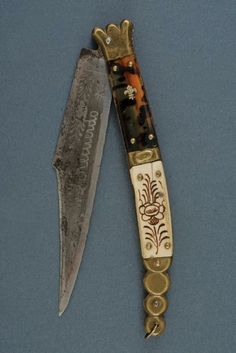 a knife with an ornate design on it and a gold colored blade next to it