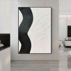 a white and black abstract painting on the wall in a modern living room with grey flooring