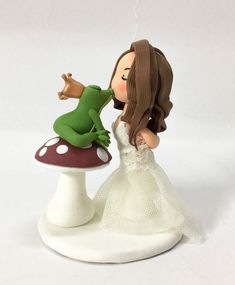 a wedding cake topper with a frog kissing a toad on it's head