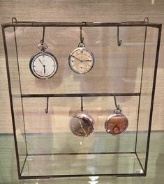 a glass display case with three clocks hanging from it's sides and two keyholes on each side