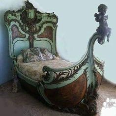 an antique bed with ornate carved wood frame and headboard, sitting against a blue wall