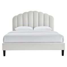 a white bed with an upholstered headboard