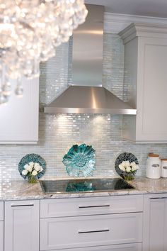 a kitchen with white cabinets and glass backsplashes on the counter top,