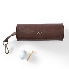 a golf ball and leather case with the word air on it next to a pair of scissors