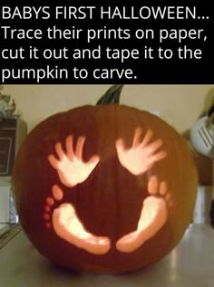 a pumpkin carved to look like a baby's first halloween, with hands on it