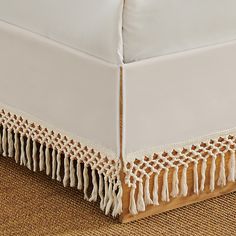 a close up of a bed with white sheets and tassels on the bottom