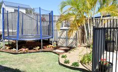 a small backyard with a trampoline in the middle and palm trees around it