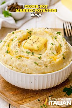 a bowl filled with mashed potatoes on top of a cutting board next to a knife and fork