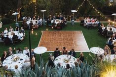 a group of people sitting at tables on top of a grass covered field next to a tennis court