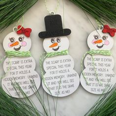 three snowmen with hats and bows on their heads are hanging from green grass in front of a white marble surface