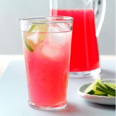 two glasses filled with watermelon and limeade sitting on a table next to a pitcher