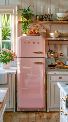 a pink refrigerator sitting in the middle of a kitchen