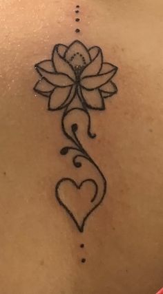 the back of a woman's neck with a flower and heart tattoo on it