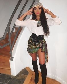 a woman is posing on the stairs with her hands in her hair and wearing thigh high boots