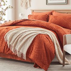 a bed with an orange comforter and pillows