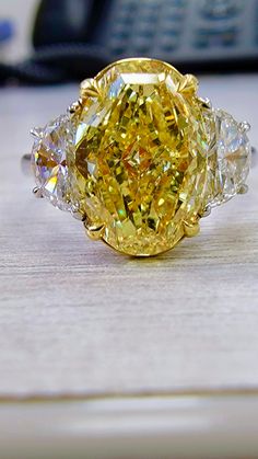 a fancy yellow diamond ring sitting on top of a table